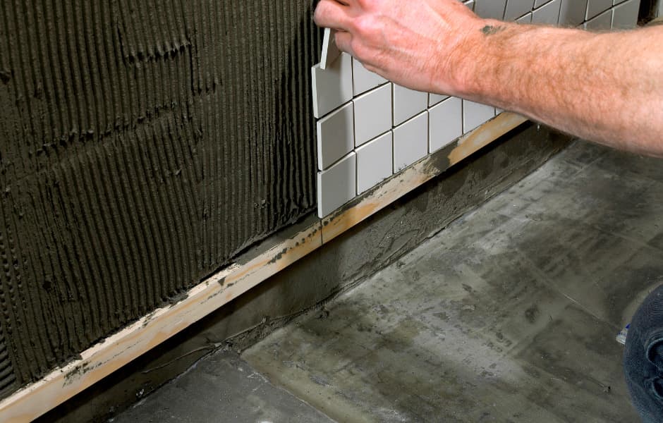 Чтобы предотвратить сползание плитки, укладка первого ряда производится на основу – это может быть ровная деревянная планка.